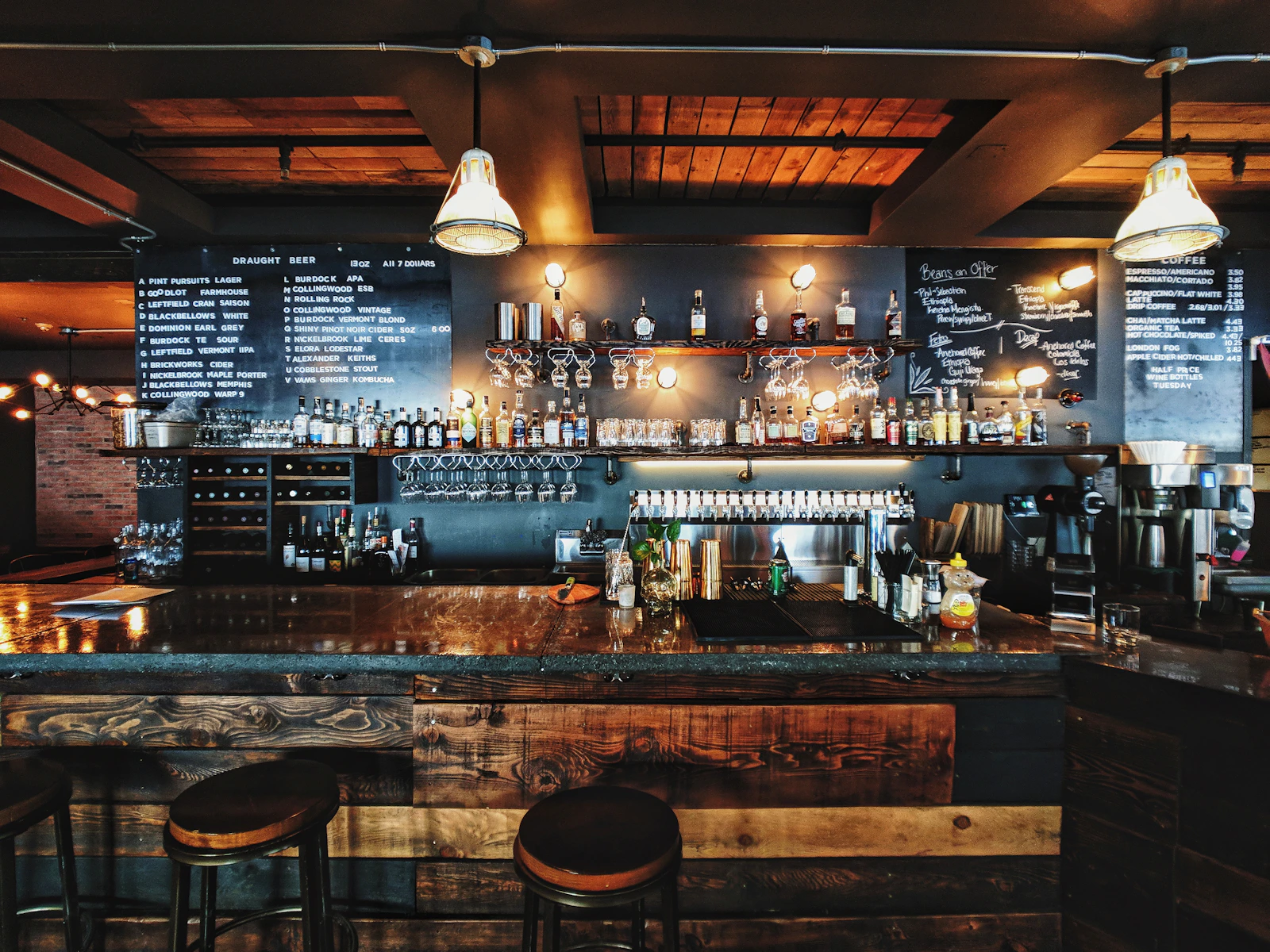 Referência de atmosfera: bar acolhedor com madeira, banquetas e iluminação quente