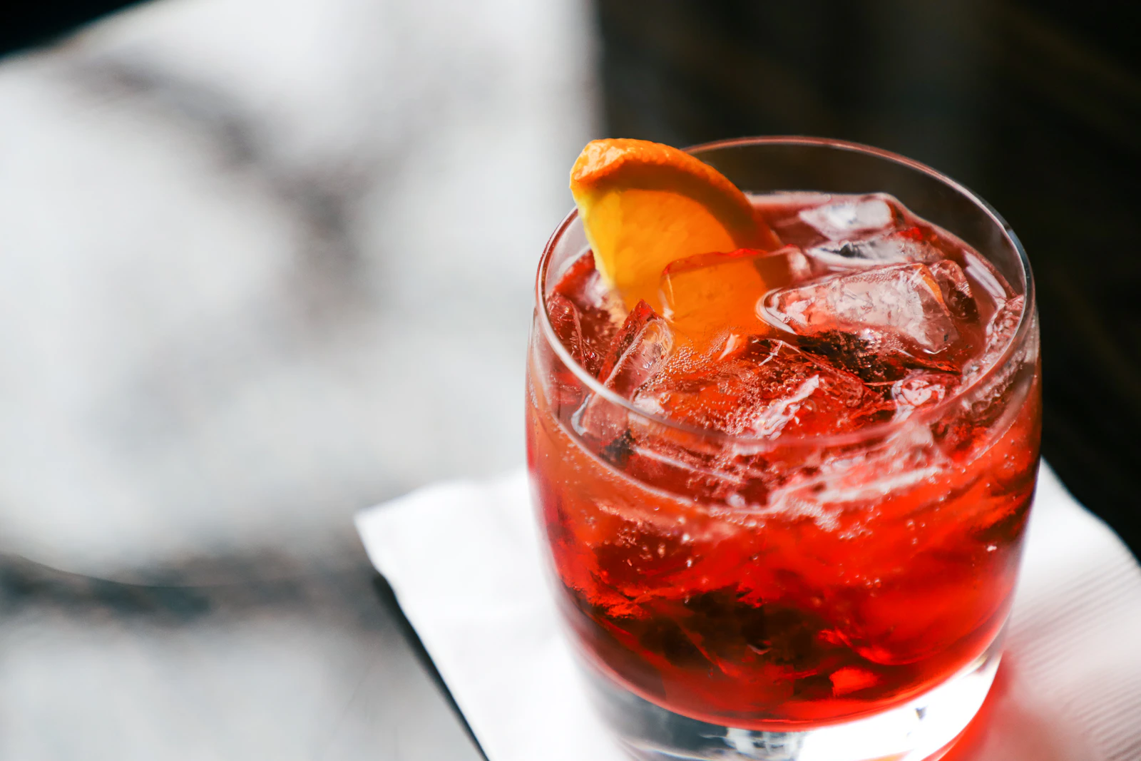 Referência de coquetelaria: um negroni avermelhado com uma fatia de laranja
